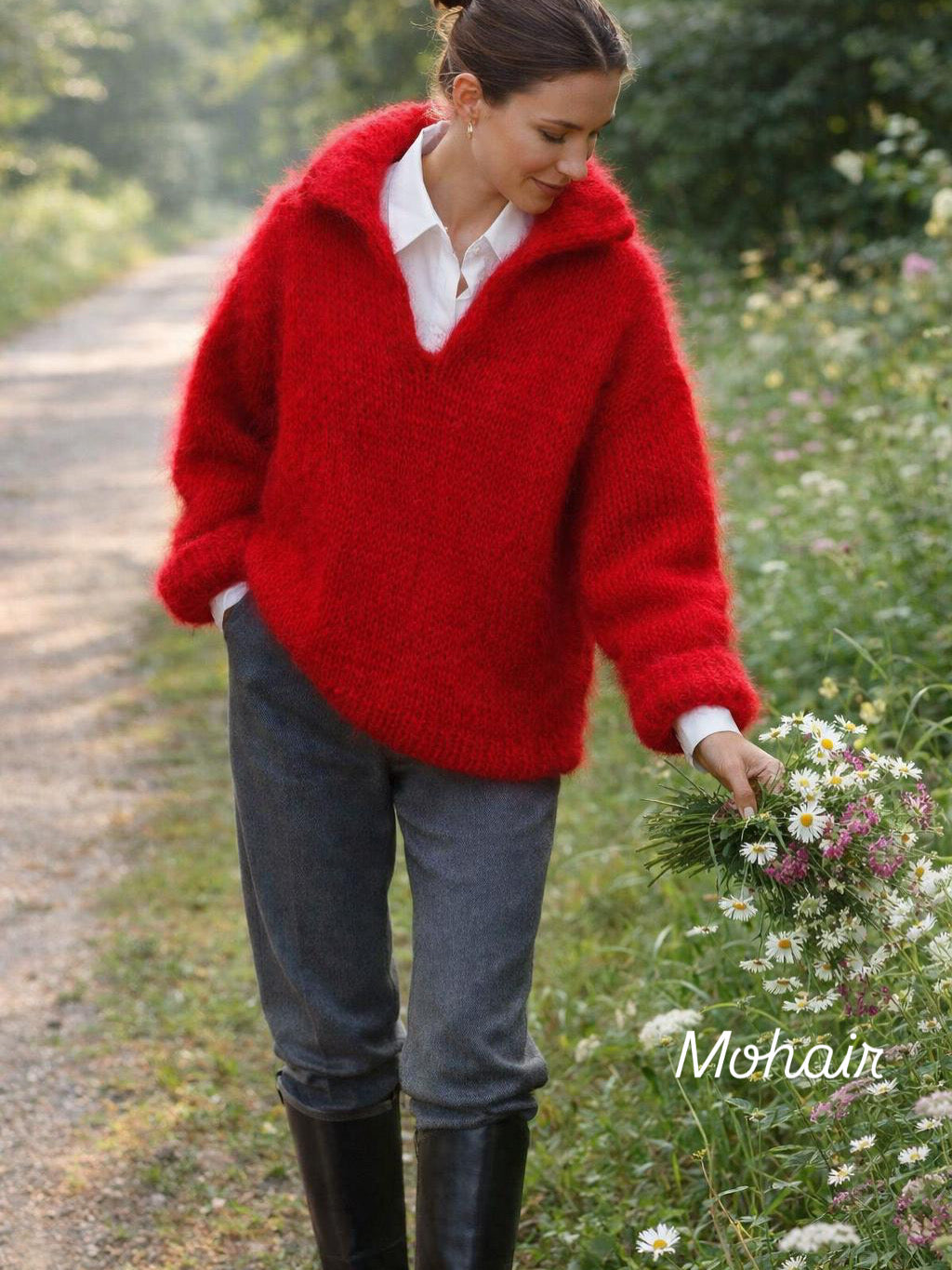Woman in a red sweater holding flowers on a path with greenery