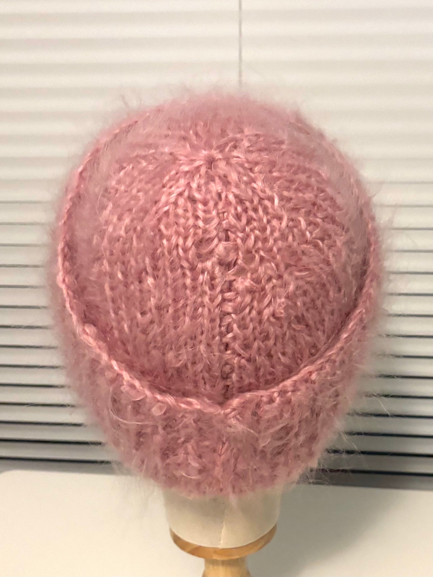 Pink knitted hat on a mannequin head against a white background