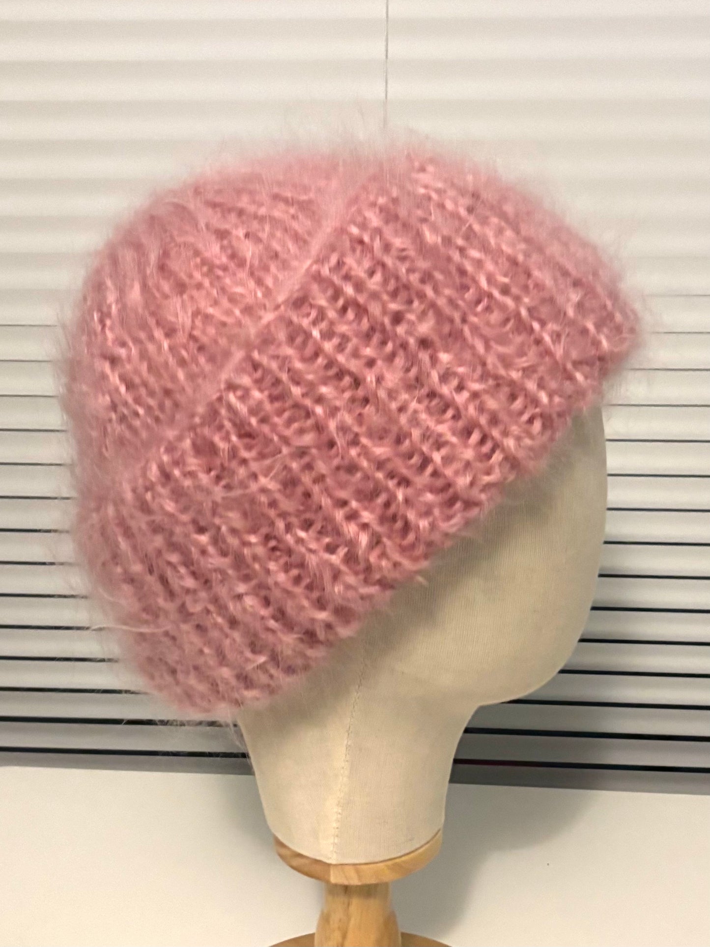 Pink knitted hat on a mannequin head against a white background