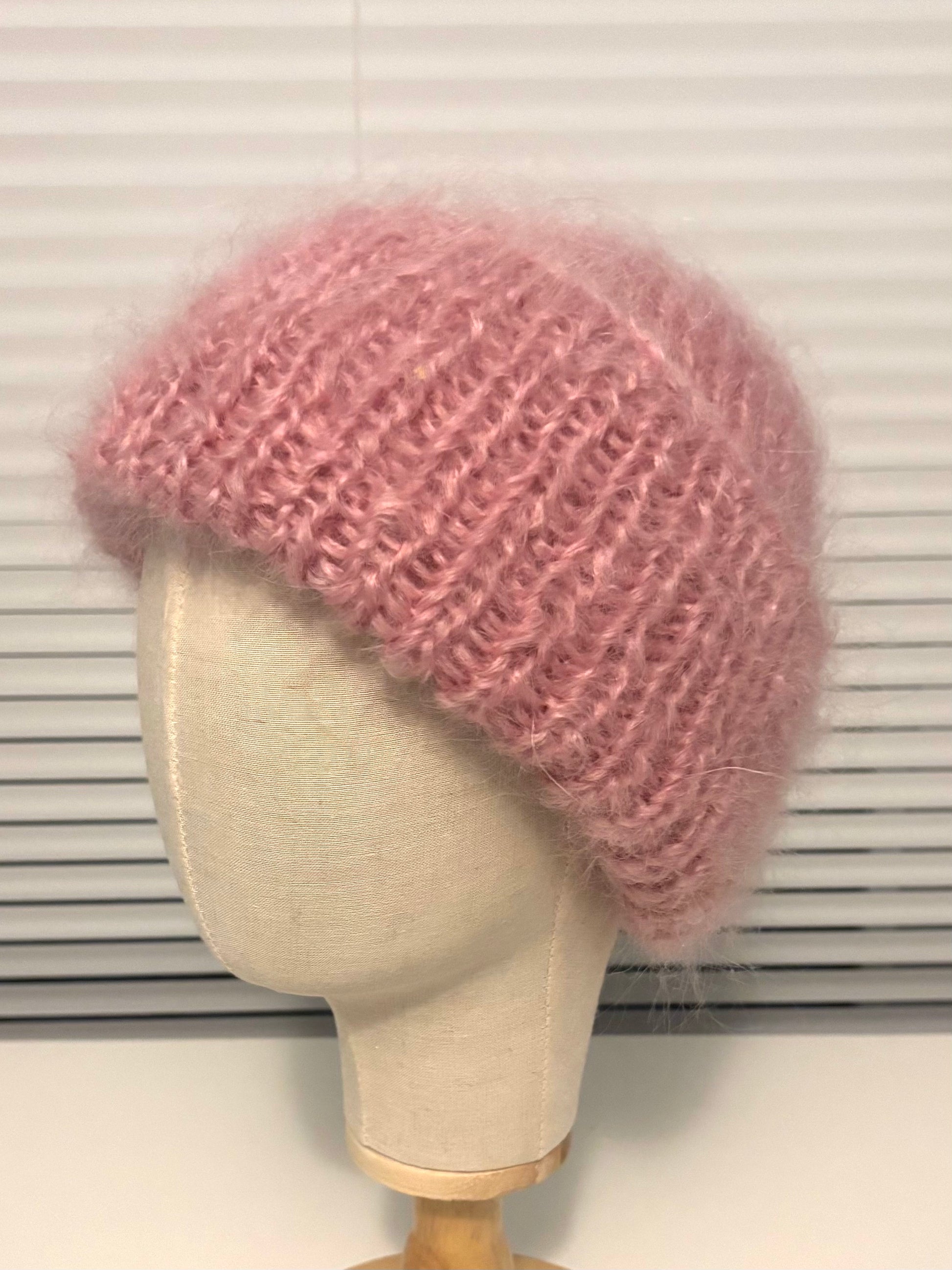 Pink knitted beanie on a mannequin head against a white background