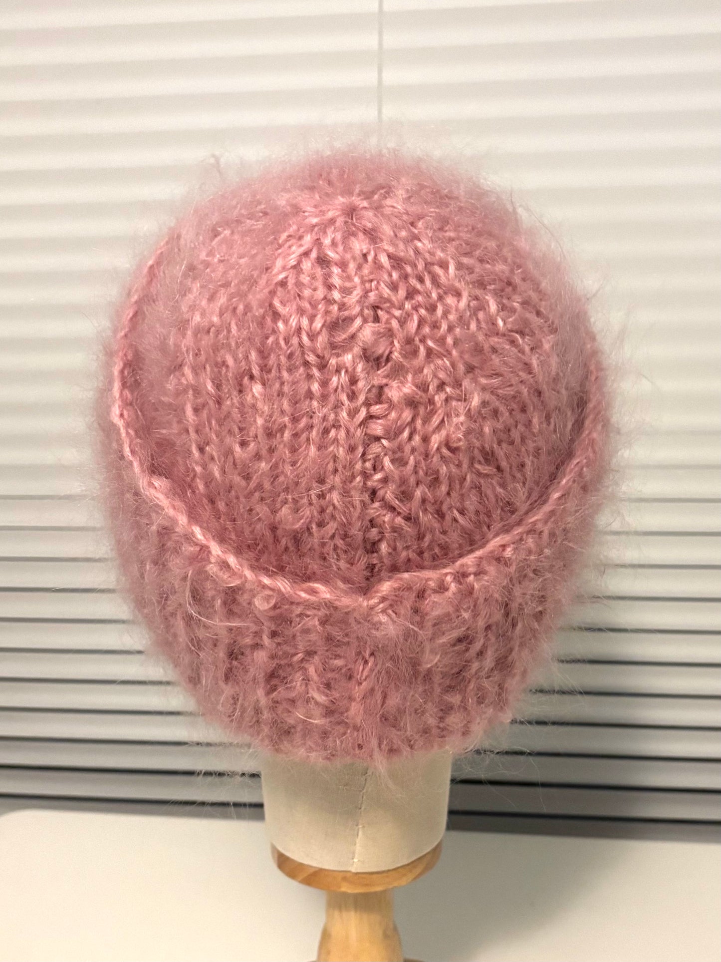 Pink knitted hat on a mannequin head against a white background