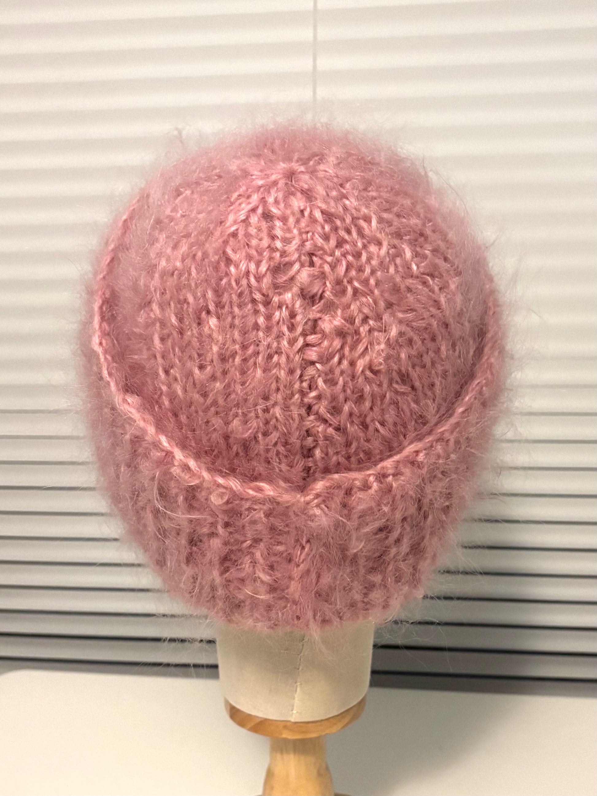 Pink knitted hat on a mannequin head against a white background