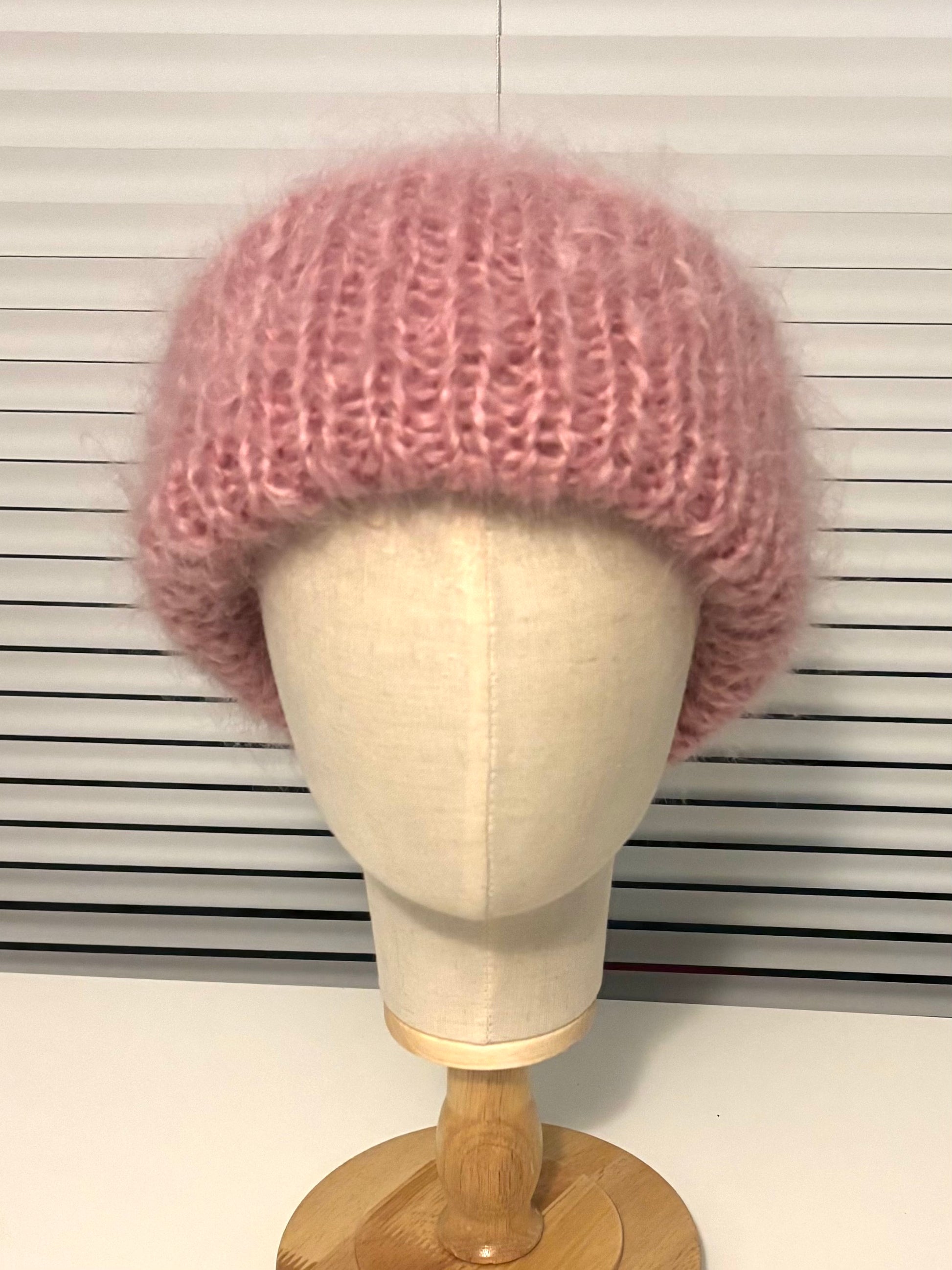 Pink knitted hat on a mannequin head against a white background