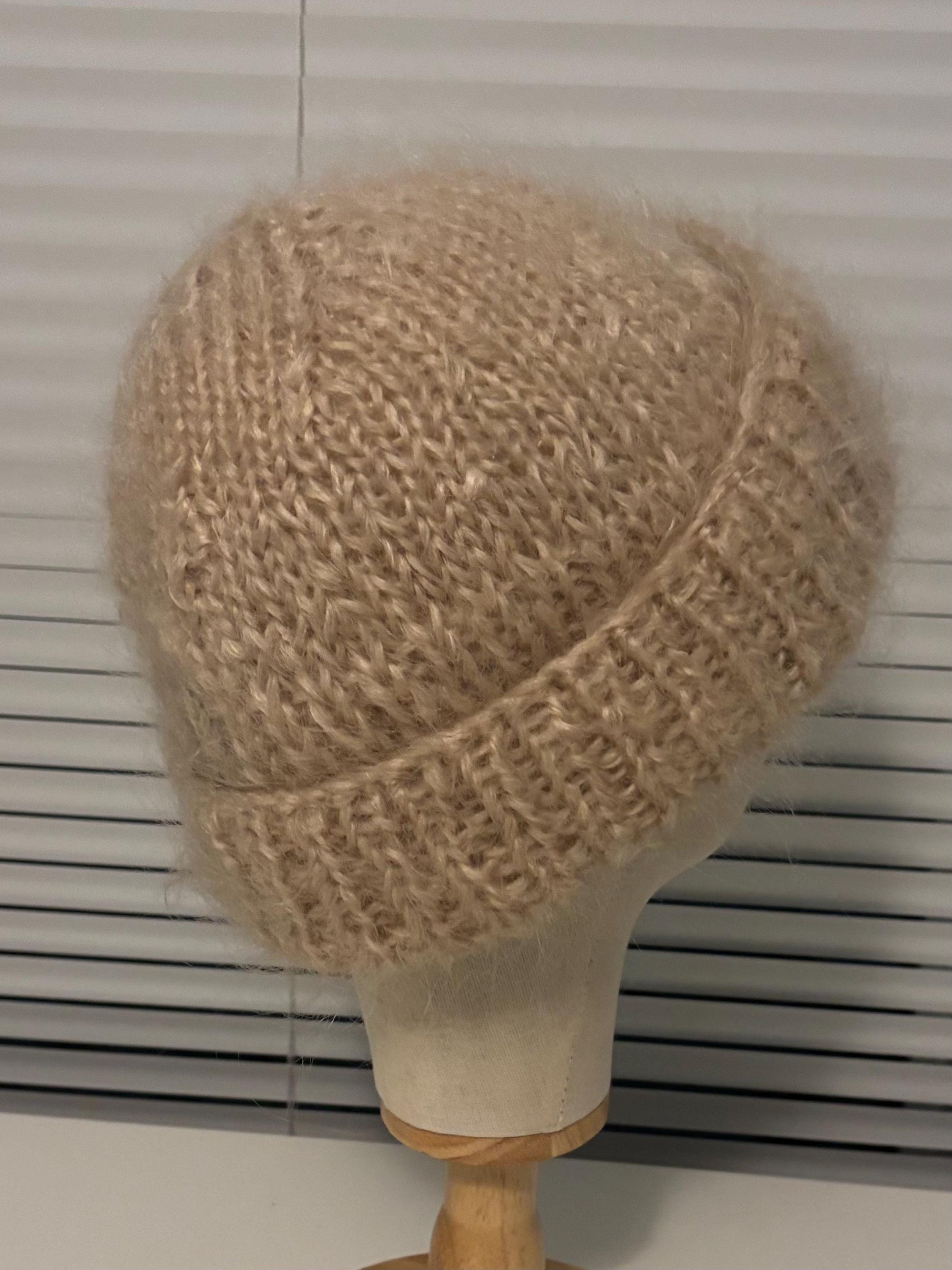 Beige knitted hat on a mannequin head against a white background