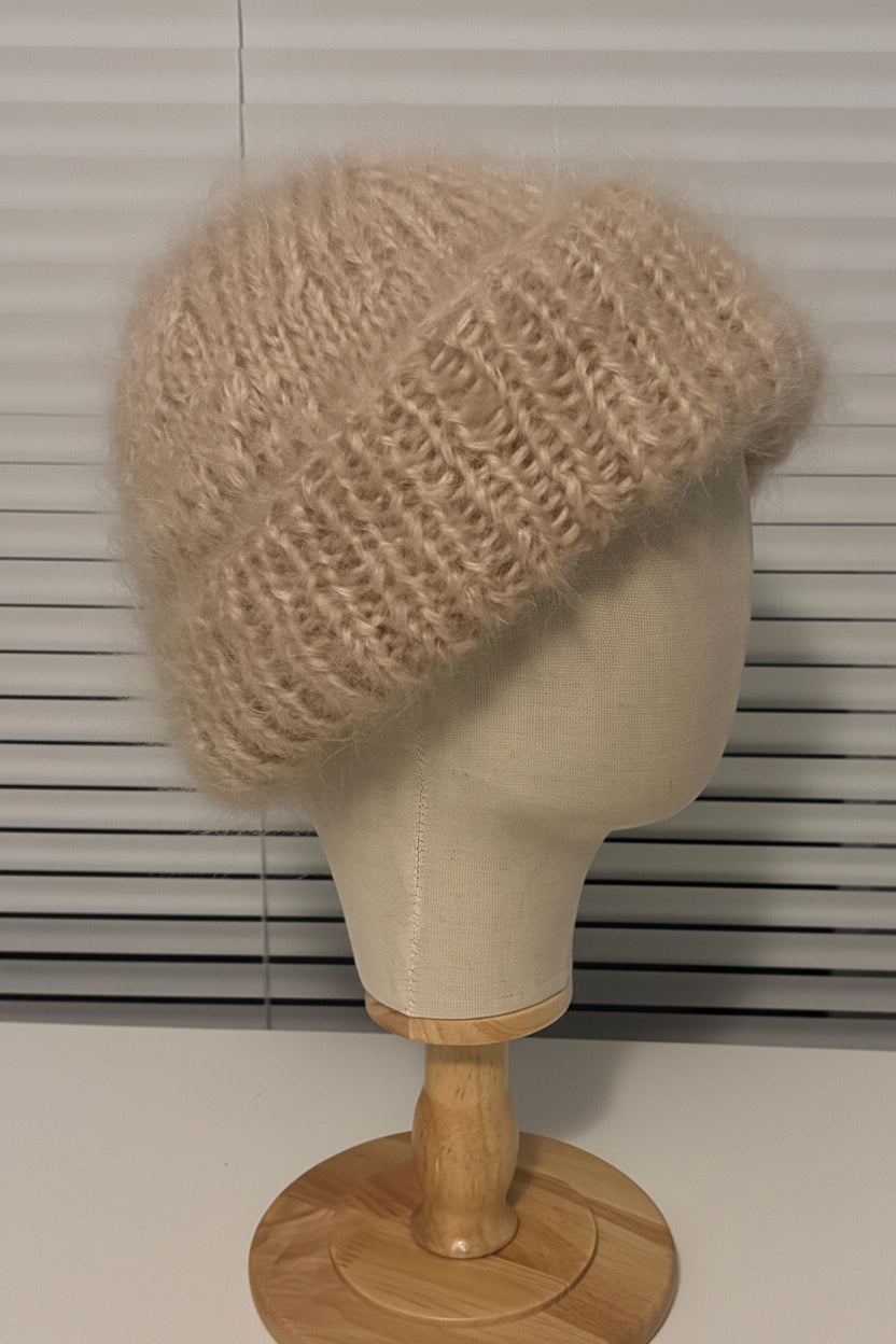 Beige knitted hat on a mannequin head against a window blind background