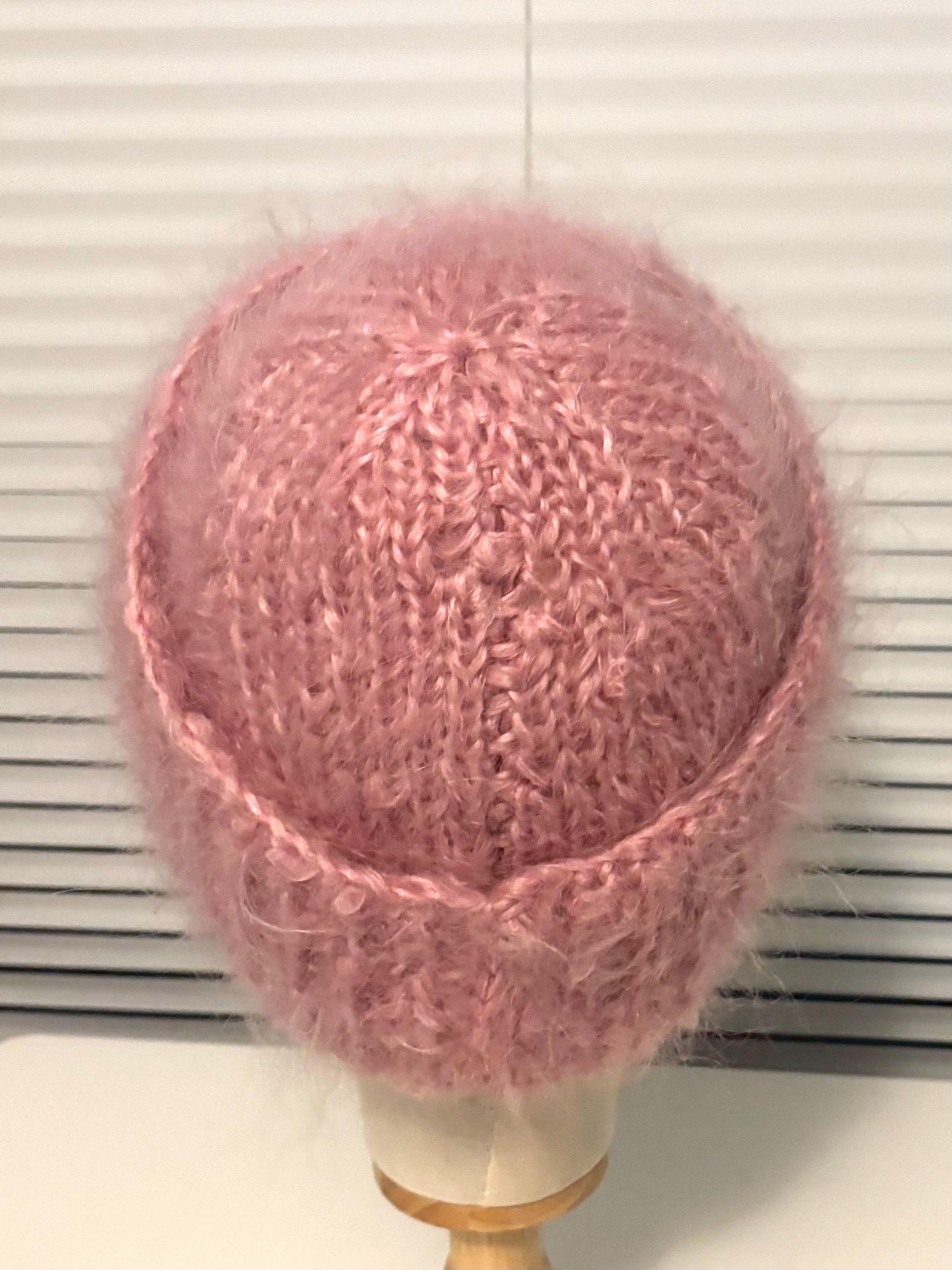 Pink knitted beanie on a mannequin head against a white background