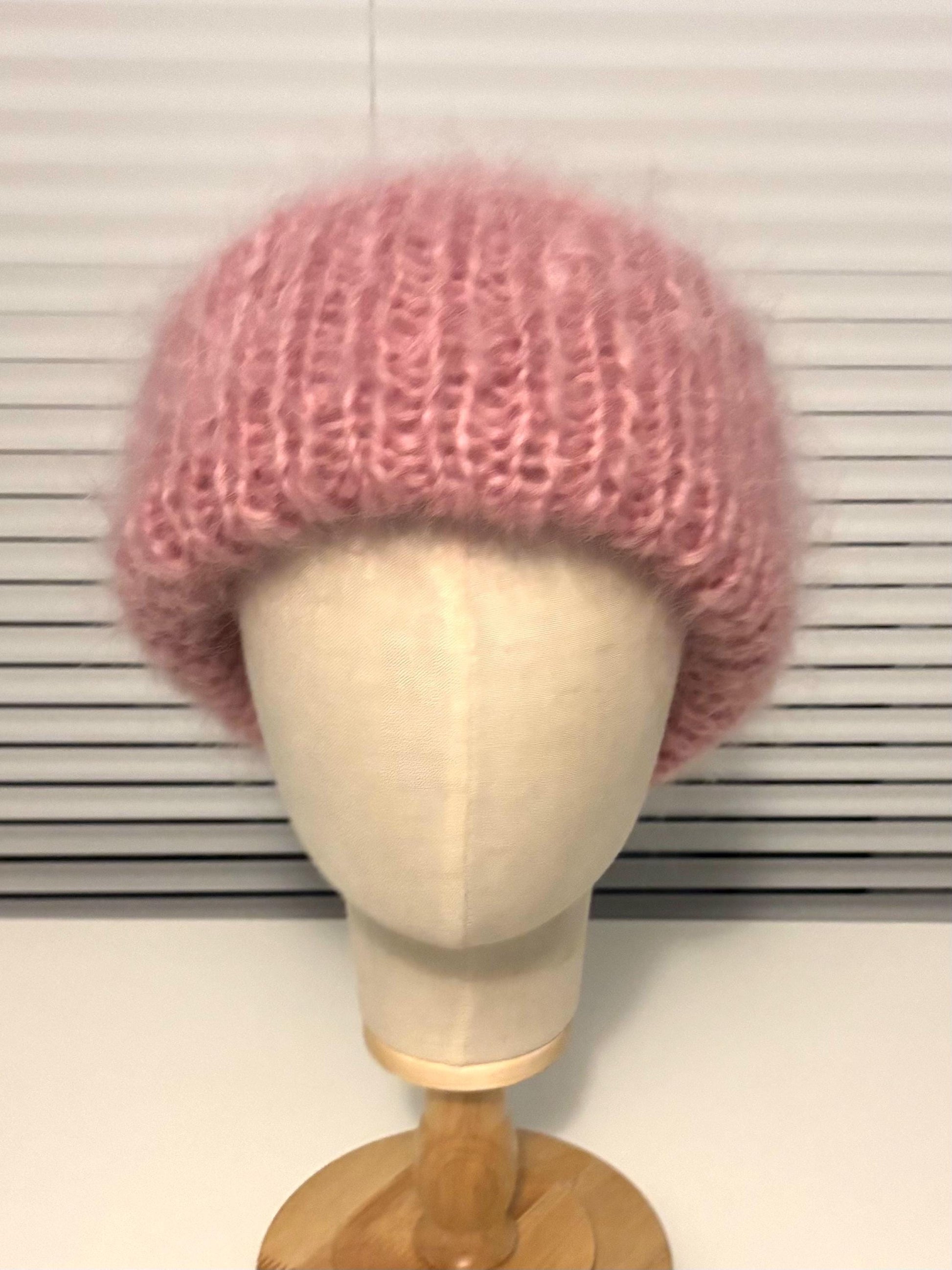 Pink knitted hat on a mannequin head against a white background